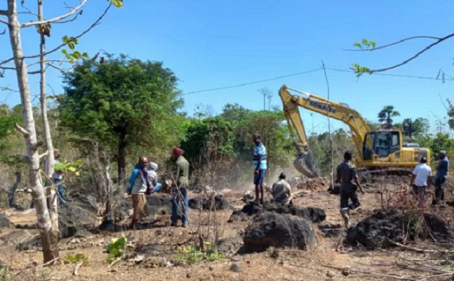 Satu unit alat berat sedang membersikan lahan yang menjadi lokasi pemakaman pasien COVID-19 di Desa Oelnasi